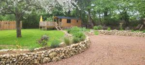 Cabaña pequeña en un patio con pared de piedra en Roulotte Escapade nature à Morainville - Normandie, en Morainville-près-Lieurey