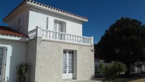 a white house with a balcony on top of it at Maison avec Jardin privé in Saint-Hilaire-de-Riez