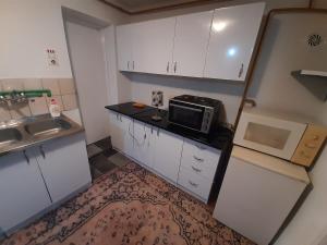 una pequeña cocina con armarios blancos y microondas en Sprat kuce en Sarajevo