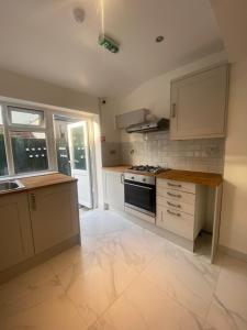 uma cozinha com armários brancos e um forno com placa de fogão em Cosy house in Newham em Londres