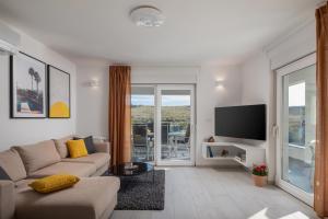 ein Wohnzimmer mit einem Sofa und einem Flachbild-TV in der Unterkunft Villa Sunset Bay - amazing view and large heated pool in Ljubač