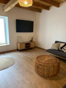 a living room with a couch and a tv on the wall at Les figuiers de Jeanne in Castelculier
