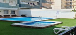 a large swimming pool on a green lawn with chairs at Exclusive Penthouse Pool & Beach - Lovely for families - Los Pinos Residential in El Campello