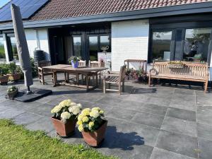 a patio with a wooden table and benches and flowers at B&B Hieris't in Hoofdplaat