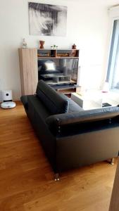 - un canapé noir dans le salon dans l'établissement Appartement lumineux Gagny - Paris banlieue, à Gagny