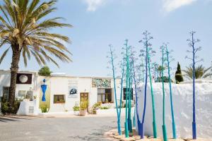 un grupo de árboles azules y verdes frente a un edificio en Casa Piedra Blanca, en Rodalquilar