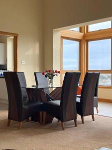 a dining room table with chairs and a vase of flowers at Apartment 500 - Metro style apartment on NC500 in Thurso