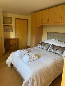 ein Schlafzimmer mit einem weißen Bett und Handtüchern darauf in der Unterkunft Apartment 500 - Metro style apartment on NC500 in Thurso