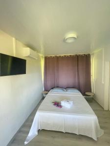 a bedroom with a white bed with a purple headboard at Temana Airport Faa'a,Tahiti in Faaa