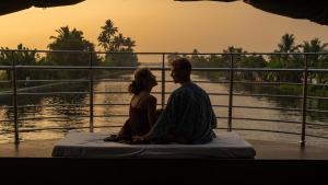 un hombre y una mujer sentados junto a un río en Kera Houseboats Alleppey, en Alleppey