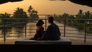 a man and a woman sitting next to a river at Kera Houseboats Alleppey in Alleppey