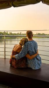 a man and woman sitting on a boat looking at the water at Kera Houseboats Alleppey in Alleppey
