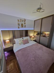 ein Schlafzimmer mit einem großen Bett mit zwei Tischen und zwei Lampen in der Unterkunft Apartman Juba in Lukavica