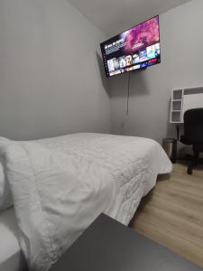 a bedroom with a white bed and a flat screen tv at Chambre privé dans une maison avec terrasse et jardin salles de bain partagées in Lille