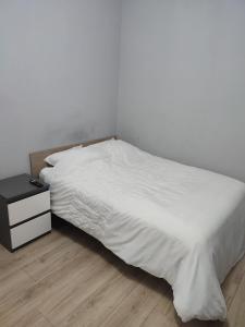 a bedroom with a white bed and a night stand at Chambre privé dans une maison avec terrasse et jardin salles de bain partagées in Lille