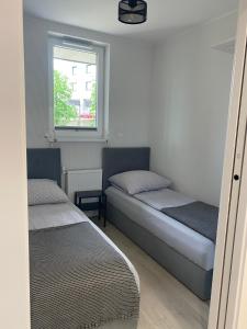 Duas camas num pequeno quarto com uma janela em Apartament MORENA em Gdansk
