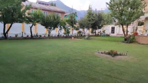 een groene tuin met bomen en een gebouw bij THE CLOVER Home Stay in Srinagar