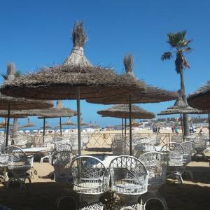 - un groupe de chaises longues et de parasols sur une plage dans l'établissement Appartement avec magnifique piscine face à la mer, à Minaret de Mansuria