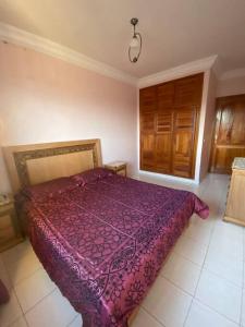 - une chambre avec une couette violette sur un lit dans l'établissement Appartement avec magnifique piscine face à la mer, à Minaret de Mansuria