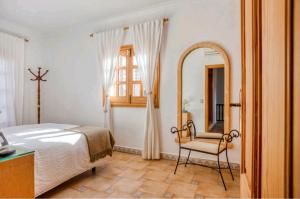 a bedroom with a bed and a mirror and a chair at SA FONTETA in S'Illot