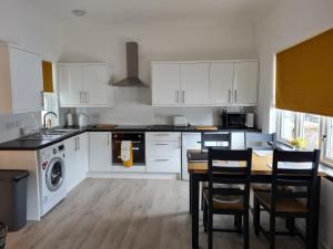 a kitchen with white cabinets and a table with chairs at 1 Golf Mews in Ballater