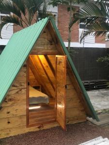 a large wooden dog house with a green roof at Hostel 4 Elementos - 200 metros da Praia de Pernambuco e do Mar Casado in Guarujá