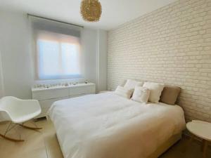 - une chambre avec un lit blanc et un mur en briques dans l'établissement Apartamento Pàmpol, à Lliber