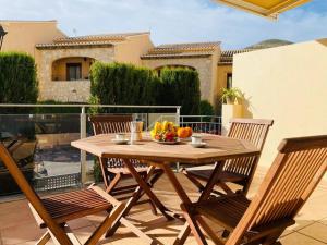 a wooden table with chairs and a bowl of fruit on a patio at Apartamento Pàmpol in Lliber