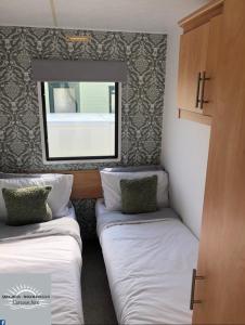 Habitación pequeña con 2 camas y espejo. en Skegness - Ingoldmells Caravan Hire en Ingoldmells