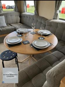 una mesa con platos y copas de vino. en Skegness - Ingoldmells Caravan Hire en Ingoldmells