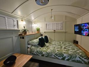 a bedroom with a bed in a room with a tv at Gatwick Hideaway Hut in Charlwood