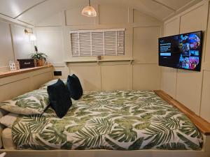 um quarto com uma cama e uma televisão na parede em Gatwick Hideaway Hut em Charlwood