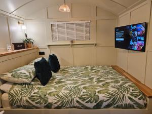 a bedroom with a bed with a tv on the wall at Gatwick Hideaway Hut in Charlwood