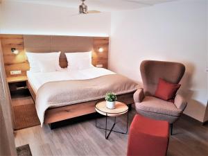 um quarto de hotel com uma cama e uma cadeira em Hotel-Restaurant Pfälzer Hof em Edenkoben