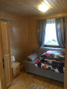 a small bedroom with a bed and a window at Domki Magnolia in Rusinowo