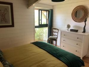 um quarto com uma cama, uma cómoda e uma janela em VILLA DOUCEUR EXOTIQUE em Lacanau