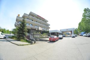 un estacionamiento con autos estacionados frente a un edificio en Hotel Le Baron, en Timisoara