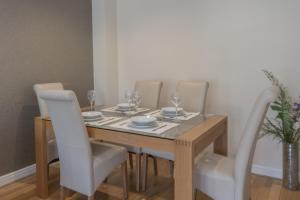 een eettafel met witte stoelen en een houten tafel met wijnglazen bij Beautiful townhouse in leafy suburb of Bradshaw in Bradshaw