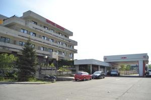 蒂米什瓦拉Hotel Le Baron的停车场前停有车辆的酒店