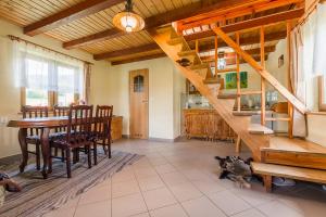 a dining room with a staircase and a table and a cat at Domek Bogdanka in Polańczyk