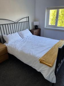 a bedroom with a white bed and a window at Lovely 3 bedroom house in Romiley, Stockport with parking for 3 cars in Romiley