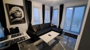 een woonkamer met een zwarte bank en ramen bij Diamond Beach Luxus Apart Obzor 28 in Obzor