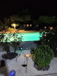 a swimming pool at night with trees and lights at jolie Mazet avec piscine privée ! in Nîmes