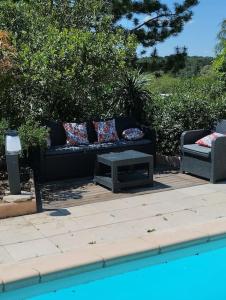 un sofá negro y una mesa junto a una piscina en jolie Mazet avec piscine privée ! en Nimes