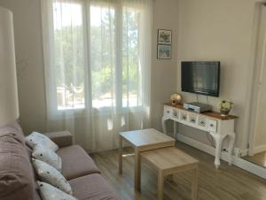 - un salon avec un canapé et une télévision sur une table dans l'établissement jolie Mazet avec piscine privée !, à Nîmes