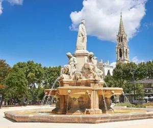 une fontaine avec une statue en face d'un bâtiment dans l'établissement jolie Mazet avec piscine privée !, à Nîmes