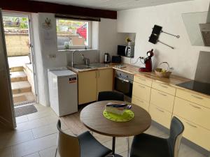 cocina con mesa, sillas y fregadero en Le Potiron en Scheidgen