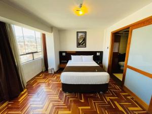 um quarto de hotel com uma cama e uma grande janela em HOTEL POLO CUSCO SUITES em Cusco