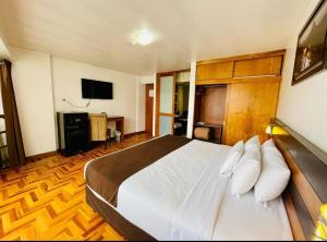 um quarto com uma cama grande e uma televisão em HOTEL POLO CUSCO SUITES em Cusco