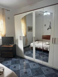 a bedroom with mirrored cabinets and a bed and a television at Sempre verde in Agnone Bagni